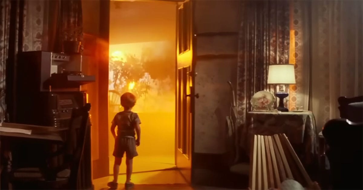 A young boy gazes at a doorway glowing with golden light in a scene from “Close Encounters of the Third Kind.”