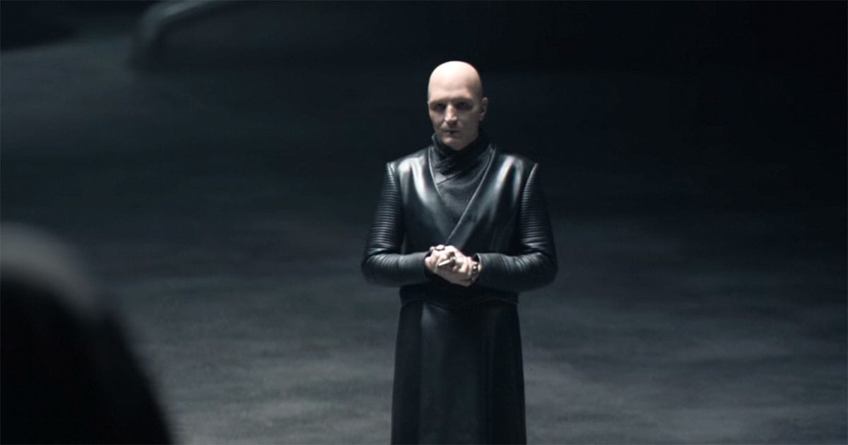 David Dastmalchian as Piter de Vries in “Dune” (2021), standing in dim light, still and analytical.