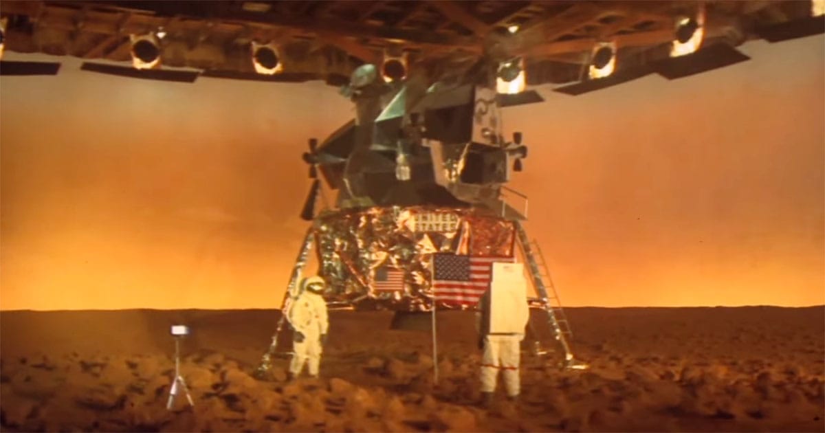 Astronauts filming a staged Mars landing on a soundstage beneath studio lights in the 1977 film Capricorn One.