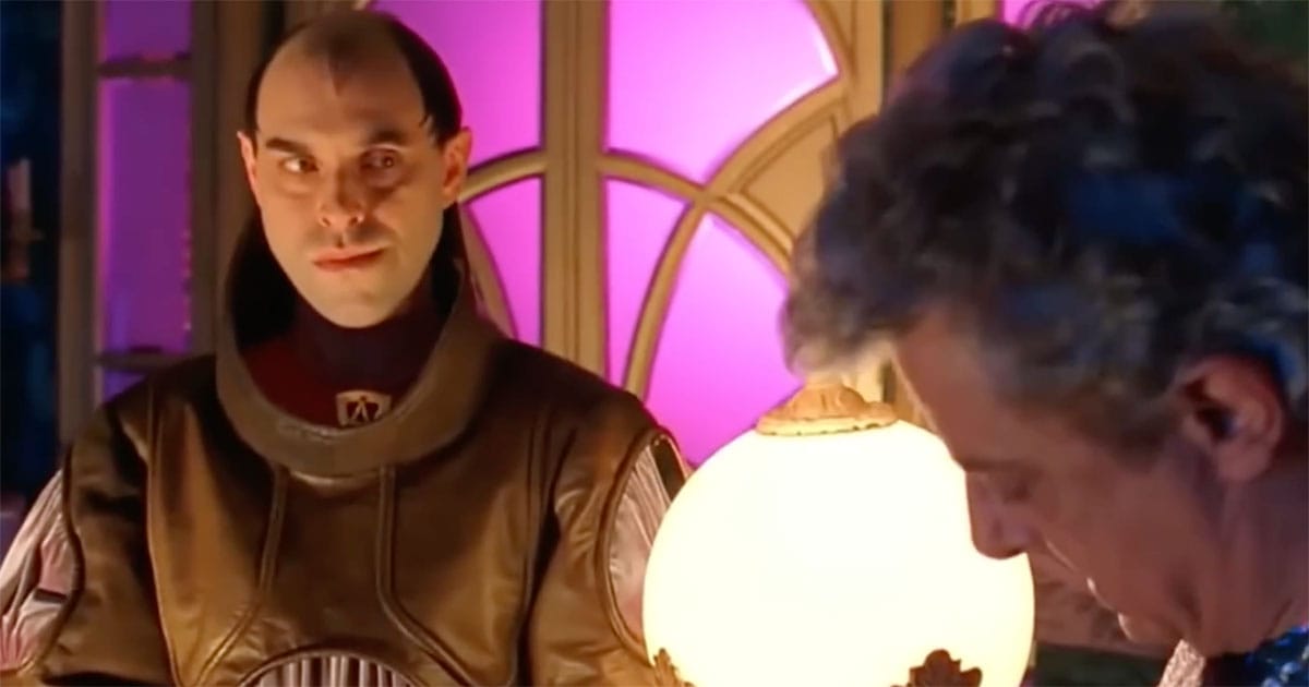 Count Hasimir Fenring standing slightly behind Emperor Shaddam IV, observing him from the side in a richly lit imperial room.