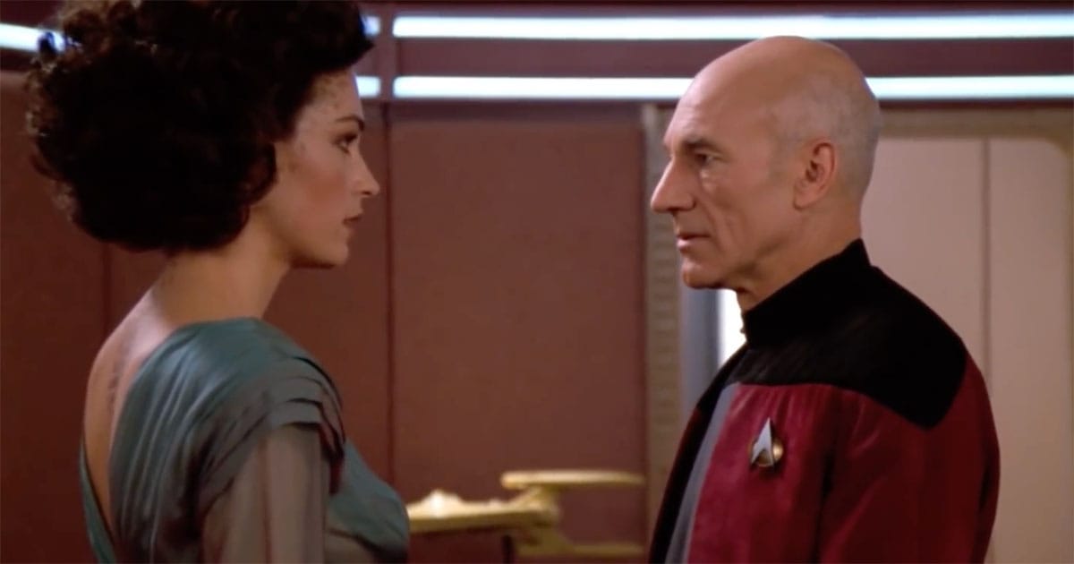 Captain Picard and Kamala stand facing one another in a quiet moment aboard the Enterprise, showing restraint and moral tension rather than physical intimacy.