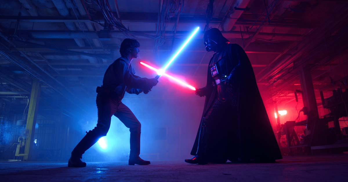 Luke Skywalker and Darth Vader crossing blue and red lightsabers in a dark industrial chamber in "The Empire Strikes Back" (1980).