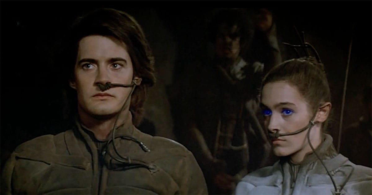 Paul Atreides and Chani standing together among the Fremen in stillsuits in a scene from "Dune" 1984.