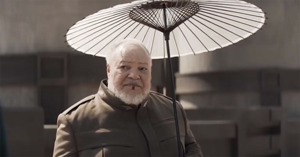Thufir Hawat standing under a parasol on Arrakis in Dune.