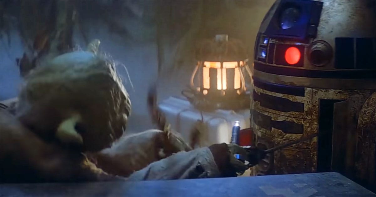 R2-D2 squeals at Yoda while they struggle over a light in a dimly lit scene from "Star Wars"