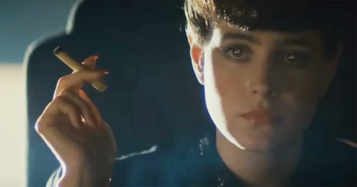 Rachael sits in shadow smoking in "Blade Runner," representing the film’s themes of hidden identity and the denial of replicant humanity