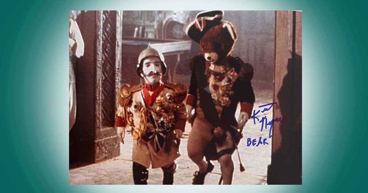 Signed Blade Runner photo featuring Kevin Thompson in costume walking beside a performer in a bear suit within a theatrical setting.