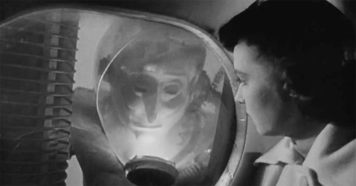 Alien visitor in helmet facing human woman in "The Man from Planet X" 1951