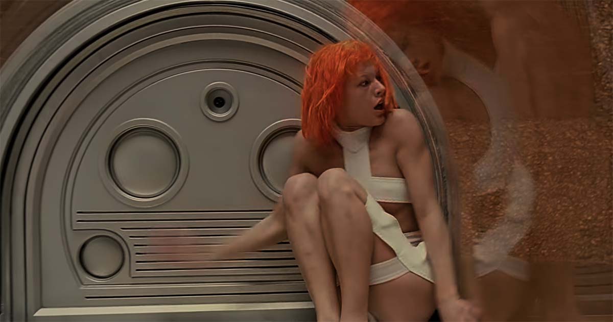 Leeloo sitting inside futuristic chamber looking to the side in The Fifth Element preparing to move.