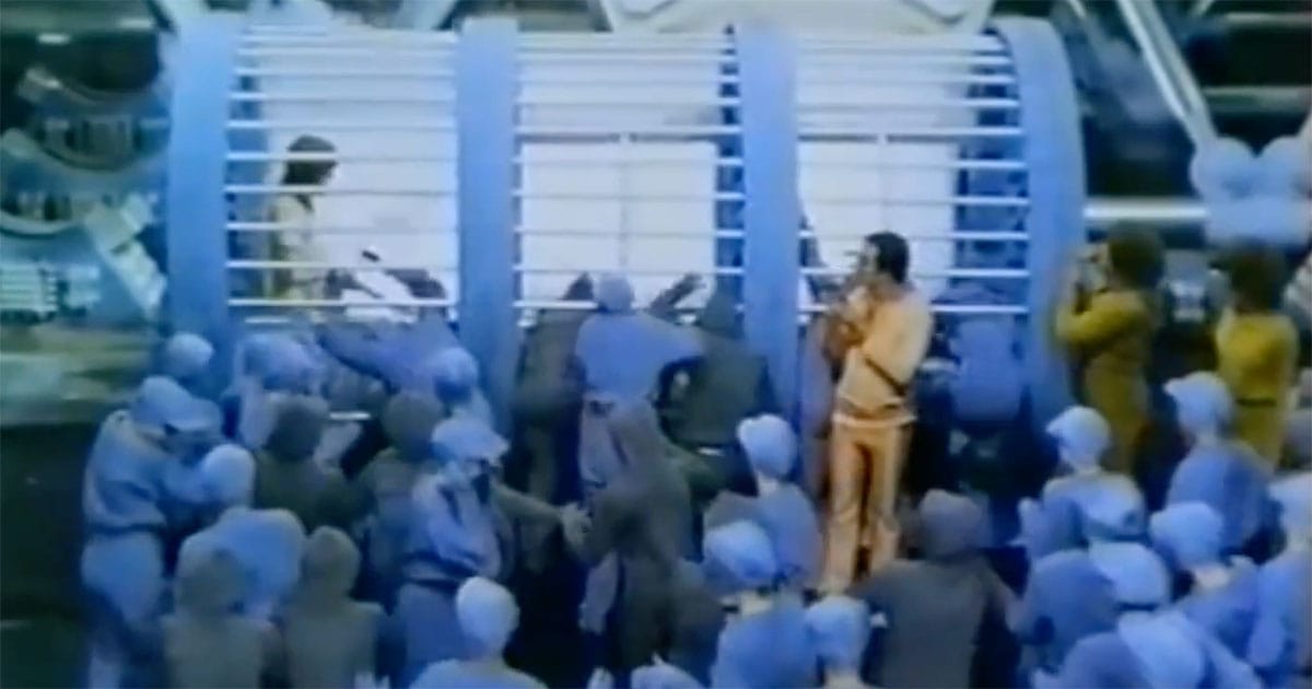 Crowd surrounding John in "Brave New World" (1980) showing societal pressure and conformity in a controlled futuristic society.