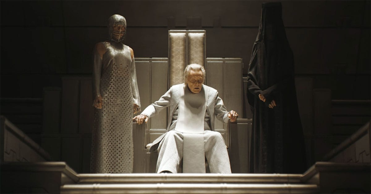 The Padishah Emperor sits on his throne while attendants stand nearby in a formal imperial chamber.