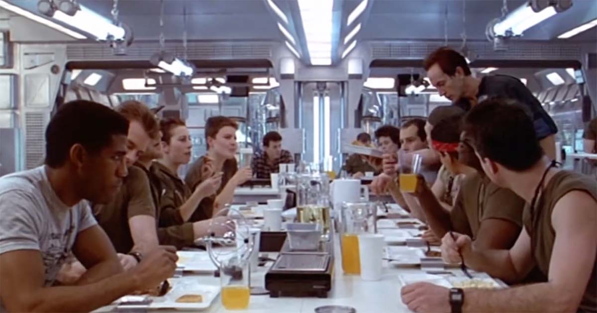 Crew members eat together in the dining area of a commercial spacecraft before their mission changes.