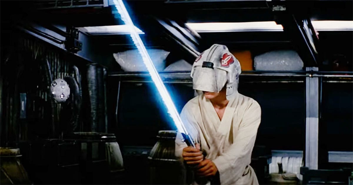 A young traveler practices with a glowing training sword while wearing a visor aboard a spacecraft.