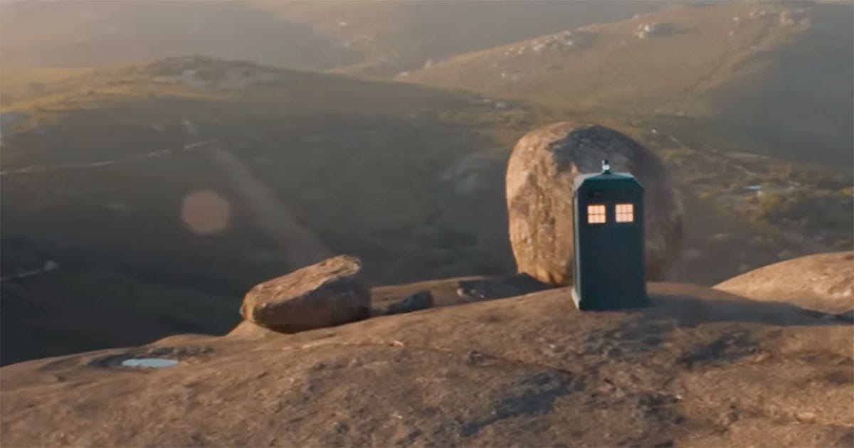 TARDIS appearing as a blue police box on a rocky landscape.
