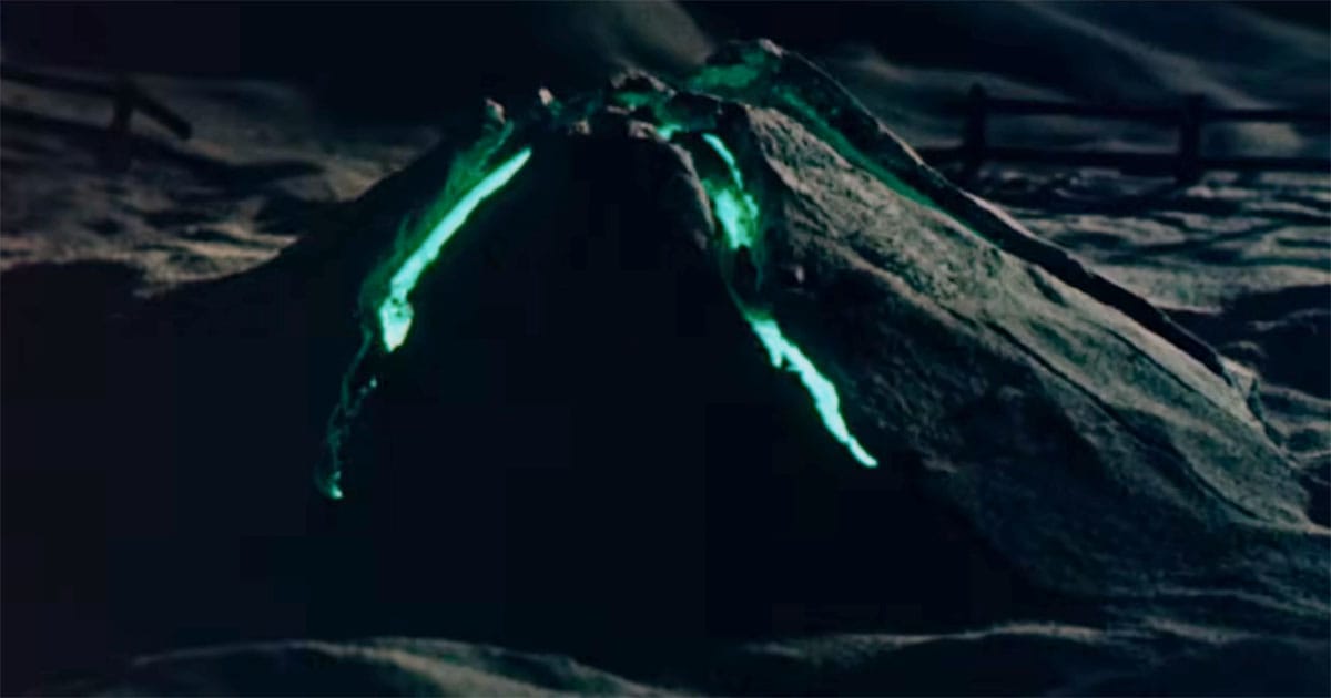Scene from "Invaders from Mars" showing a glowing hill at night with green light seeping through, indicating a buried alien presence and an enduring hidden threat.