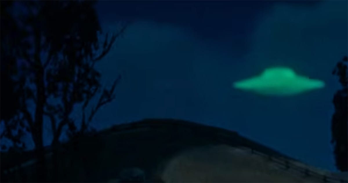 Scene from "Invaders from Mars" showing a glowing flying saucer hovering over a hill at night, as seen from a distance, suggesting a moment of discovery.