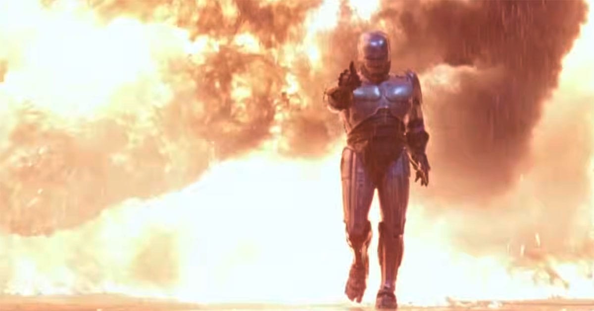RoboCop walks toward the camera through a massive explosion while wearing his silver cybernetic armor in a scene from the 1987 science fiction film "RoboCop".