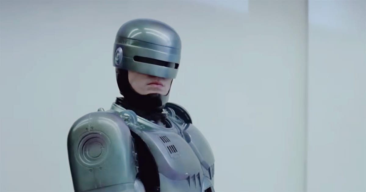RoboCop stands in a bright laboratory wearing his silver cybernetic armor and helmet in a scene from the 1987 film "RoboCop".