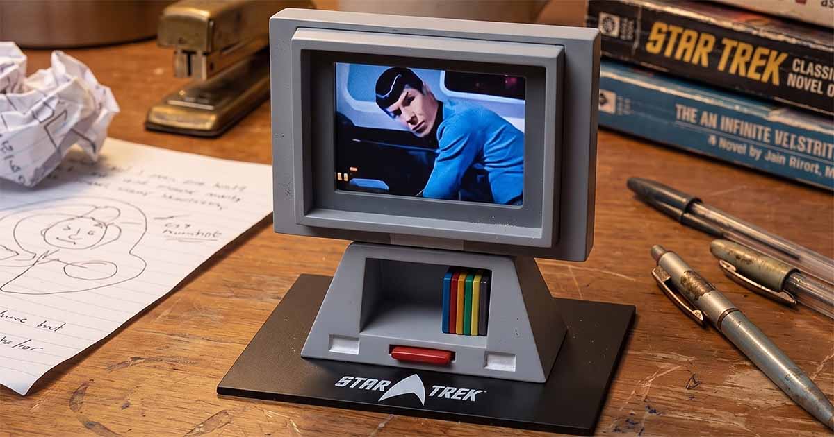 Star Trek desktop viewer prop replica displaying Spock on a small monitor while resting on a desk surrounded by books, papers, and writing instruments.