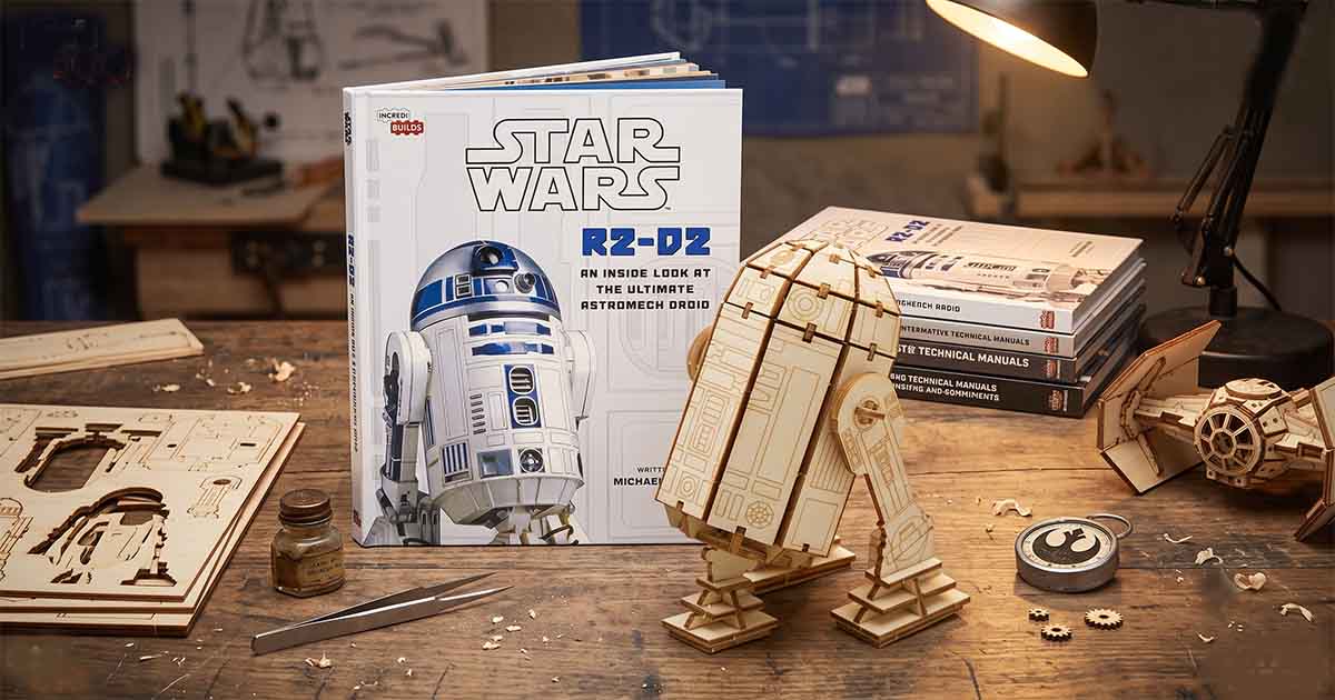 Wooden R2-D2 puzzle model beside the official IncrediBuilds "Star Wars" R2-D2 book on a workbench.