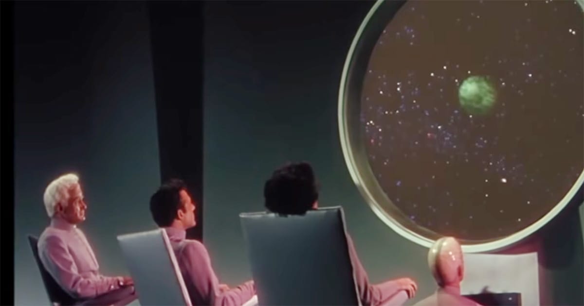 Exeter, Cal Meacham, Ruth Adams, and a Metalunan observer watch the distant planet Metaluna through a giant observation window aboard an alien spacecraft.