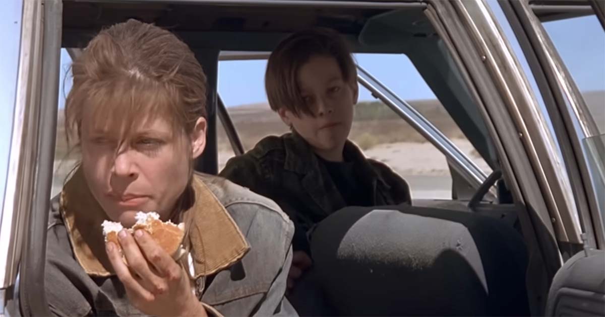 Sarah Connor eats beside a car while John sits alone in the back seat.