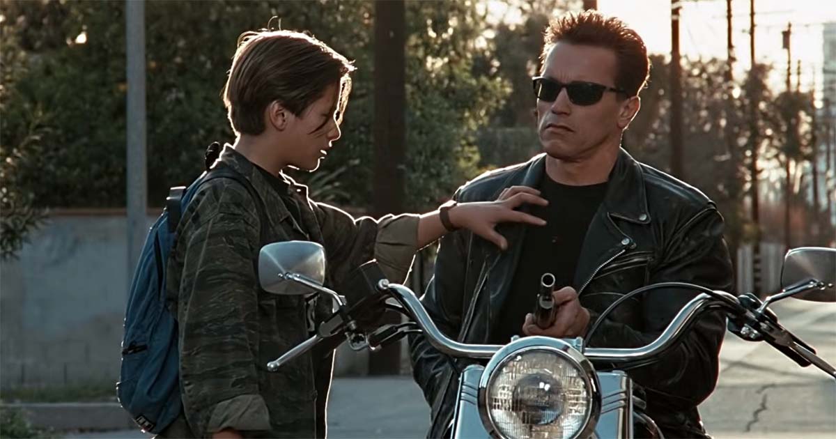 John restrains the armed T-800 beside a motorcycle.