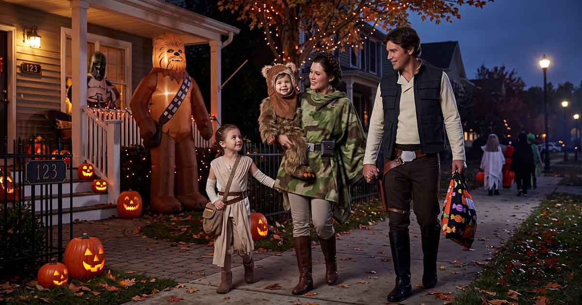 Baby dressed as an Ewok trick-or-treating with a family in Star Wars costumes.