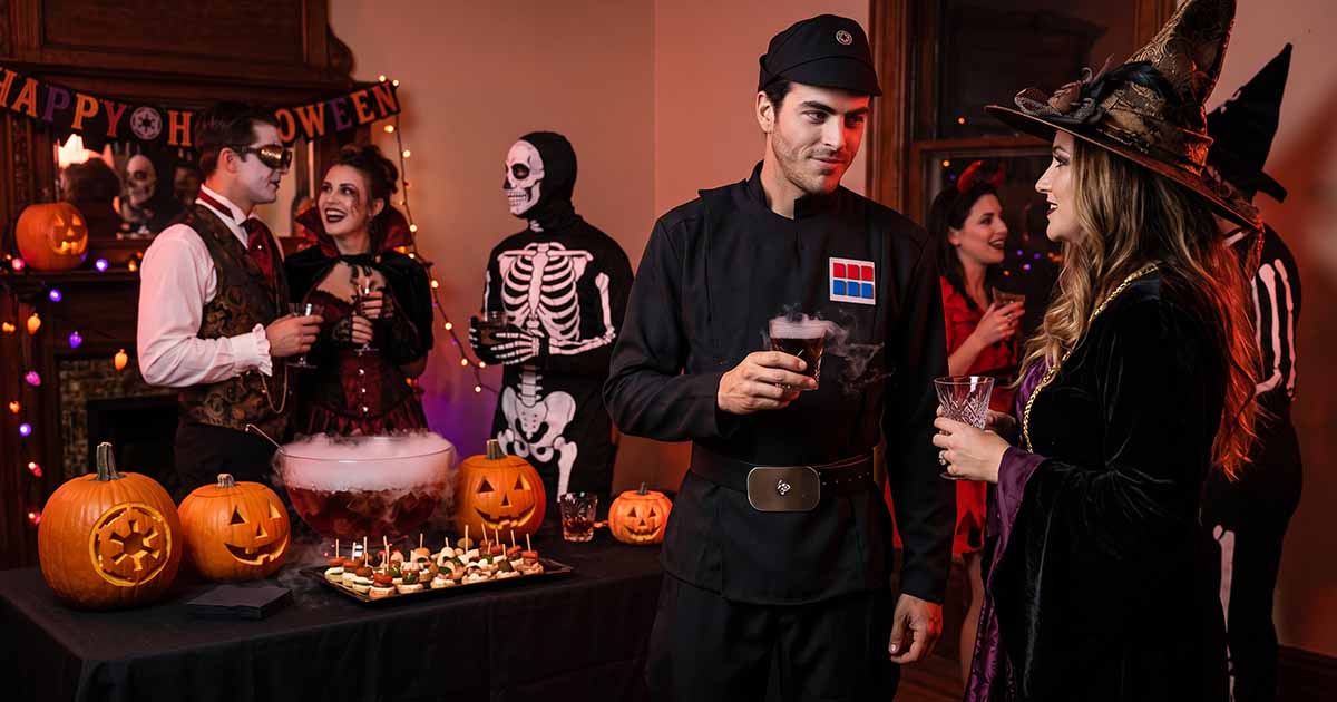 Man dressed as an Imperial officer at a Halloween party with costumed guests and carved pumpkins.