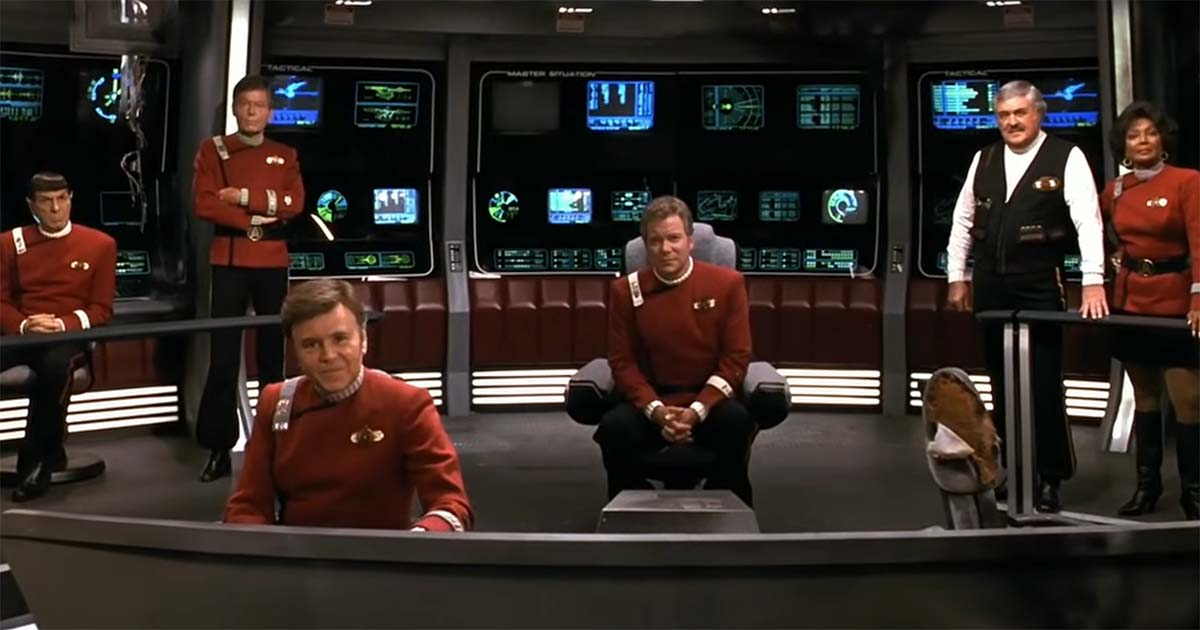 Kirk, Spock, McCoy, Scotty, Uhura, and other Enterprise crew members gathered together on the bridge.