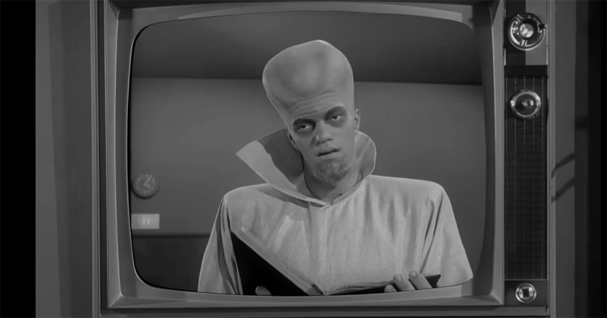 A Kanamit holds an open book on a television screen in "To Serve Man," an episode of "The Twilight Zone."