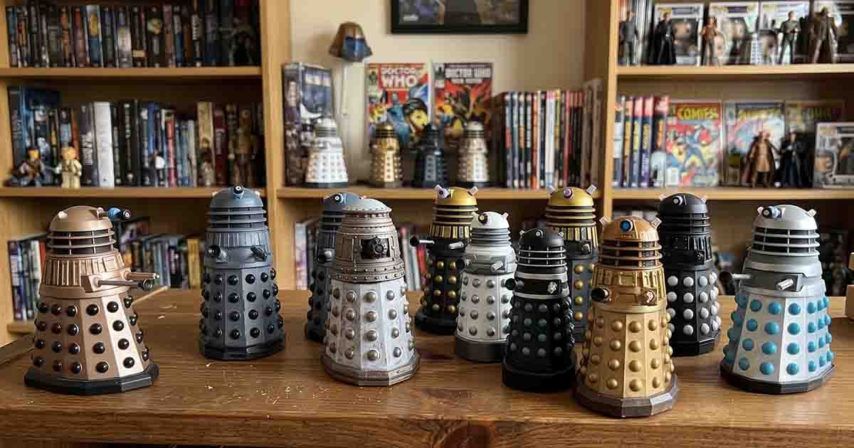 Collection of "Doctor Who" Dalek figurines in different colors displayed on a wooden table with science fiction collectibles behind them.