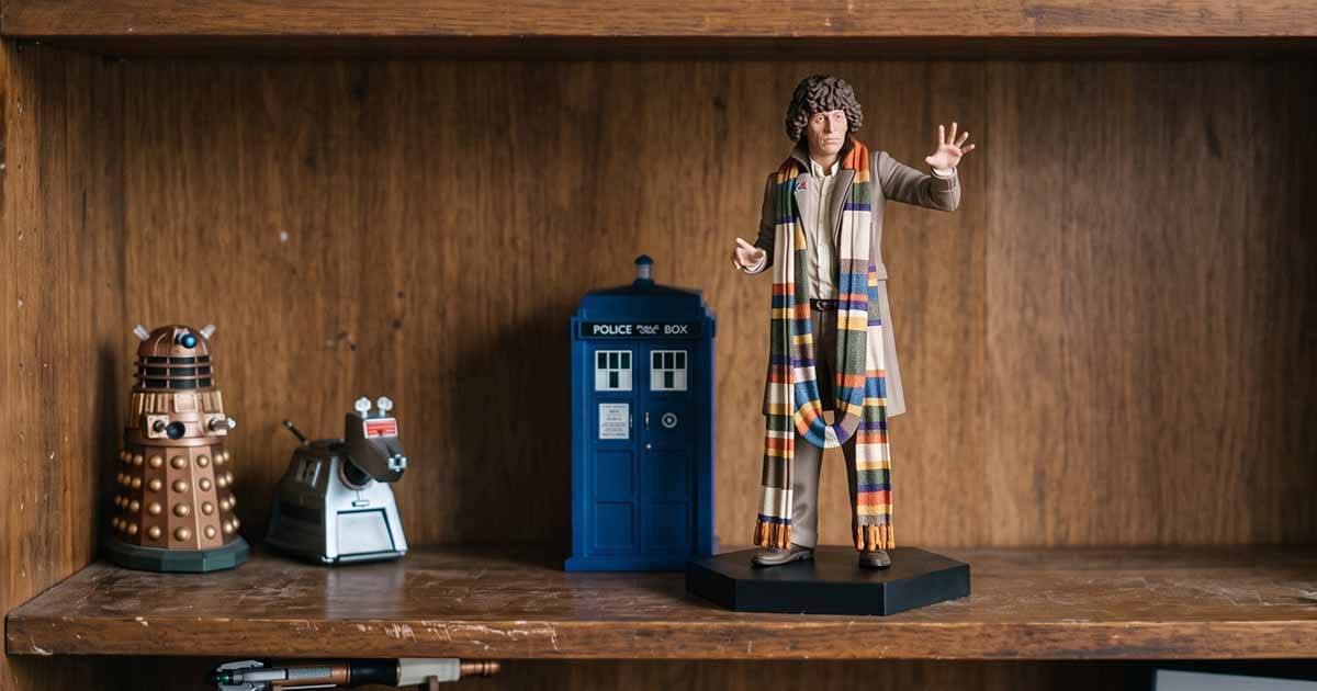 Fourth Doctor collectible figure with his multicolored scarf displayed beside a TARDIS, Dalek, and K-9 figures.