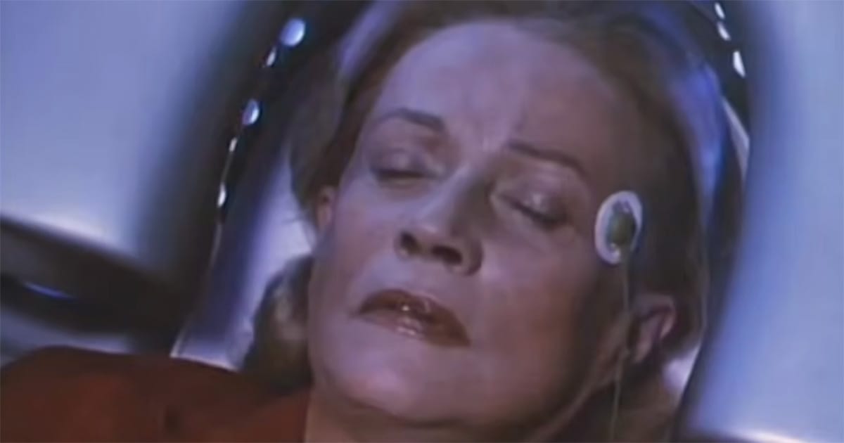 Woman resting beneath experimental equipment with a sensor attached beside her eye in "Until the End of the World" (1991).