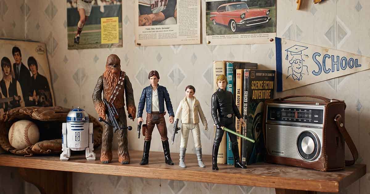 R2-D2, Chewbacca, Han Solo, Princess Leia, and Luke Skywalker action figures displayed together beside vintage books and a radio.