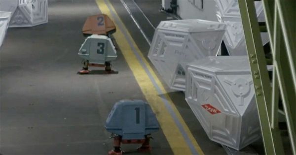 Three service drones labeled 1, 2, and 3 from the film "Silent Running" walk down a spaceship corridor lined with futuristic cargo crates.