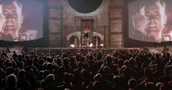 Crowd watches propaganda screens during a totalitarian rally in the 1984 film adaptation of George Orwell’s Nineteen Eighty-Four.