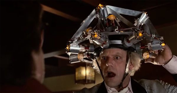 Christopher Lloyd as Doc Brown wearing a bizarre, homemade mind-reading helmet in "Back to the Future," looking surprised mid-experiment.