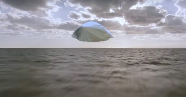 The alien spaceship from Flight of the Navigator flies over the ocean at sunset.