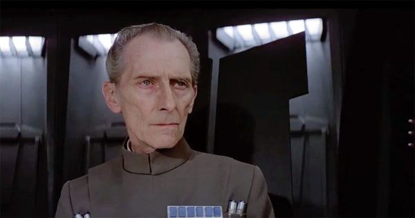 Peter Cushing portraying Grand Moff Tarkin in "Star Wars" with his upper body visible in an Imperial command setting