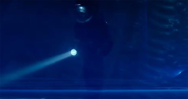 Astronaut Kane exploring alien egg chamber lit by blue laser beams in "Alien" (1979)