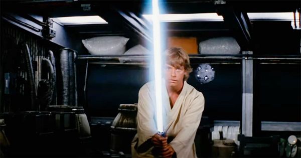 Luke Skywalker holds a glowing lightsaber during a training scene in "Star Wars" (1977), created with a practical rod coated in reflective Scotchlite tape.