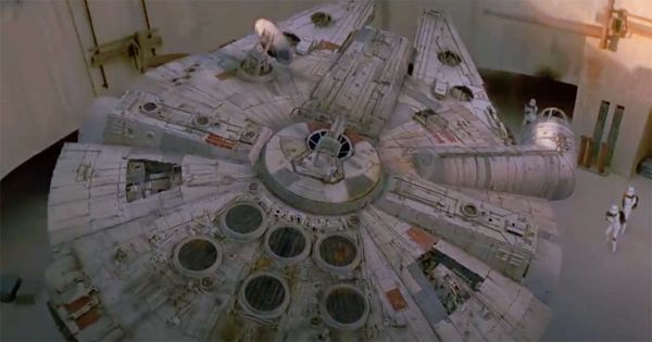 Millennium Falcon parked in Mos Eisley hangar with stormtroopers approaching.