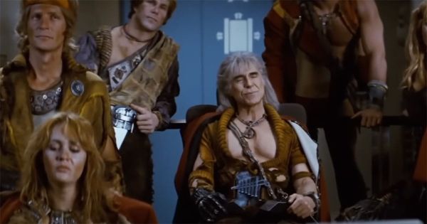 Khan seated aboard the Reliant surrounded by his ragtag followers, wearing scavenged garments and a confident expression, from "Star Trek II: The Wrath of Khan."