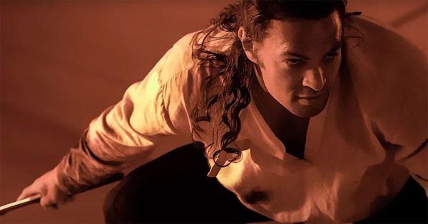 Duncan Idaho crouches in readiness within the burning light of Arrakis, blade drawn as the desert glows around him.