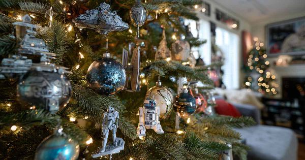 Sci fi themed christmas tree decorated with starship and droid ornaments in a softly lit living room.