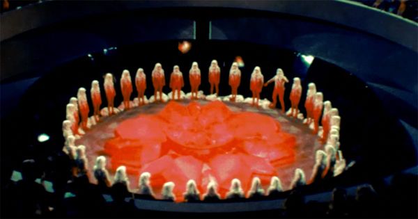 Carrousel ceremony with citizens standing in a circle around the red renewal flower in the 1976 science fiction film Logan’s Run.
