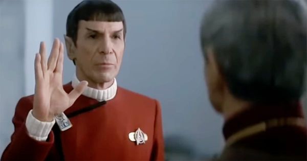 Spock raises the Vulcan salute while facing his father Sarek aboard a Starfleet vessel.
