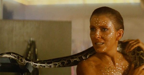 Zhora, a replicant in "Blade Runner," prepares to flee while holding a snake during a tense confrontation scene.
