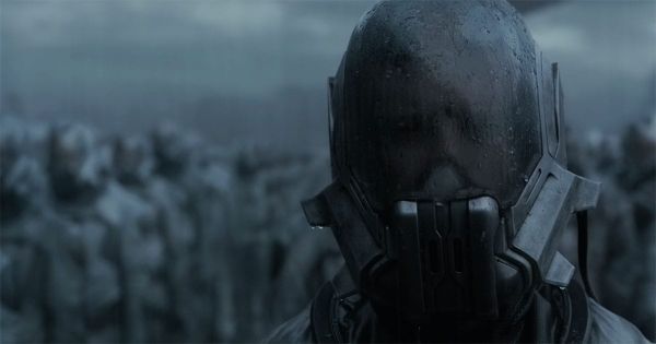 Close view of a helmeted Sardaukar soldier standing before rows of blurred imperial troops under a dark sky.